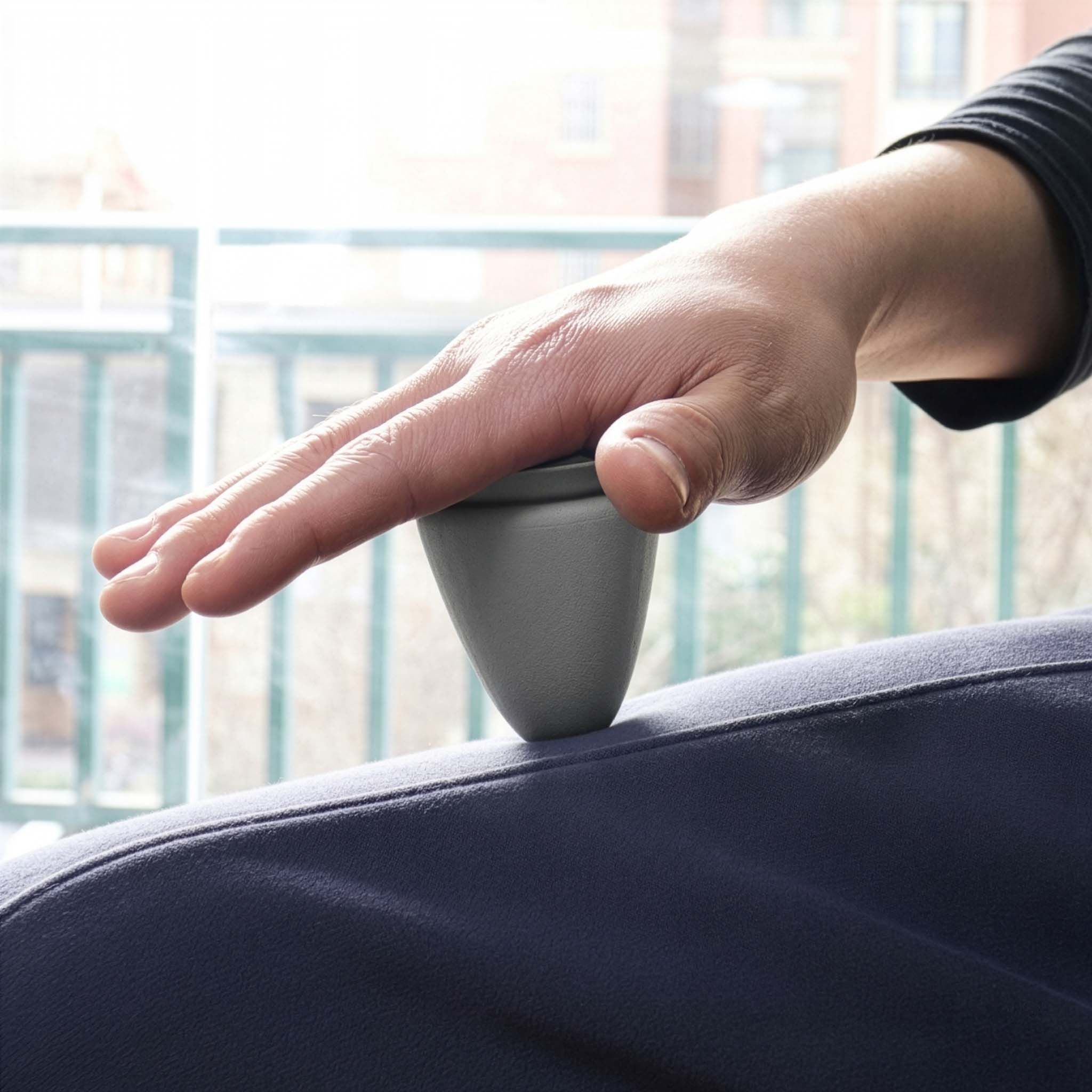 Prodotto grigio a forma di cono posto sulla coscia di una persona. Mano sul prodotto.