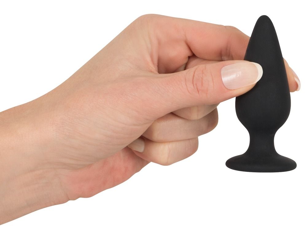 Mano che tiene un plug anale nero. Forma conica, base ampia. Colore della pelle.