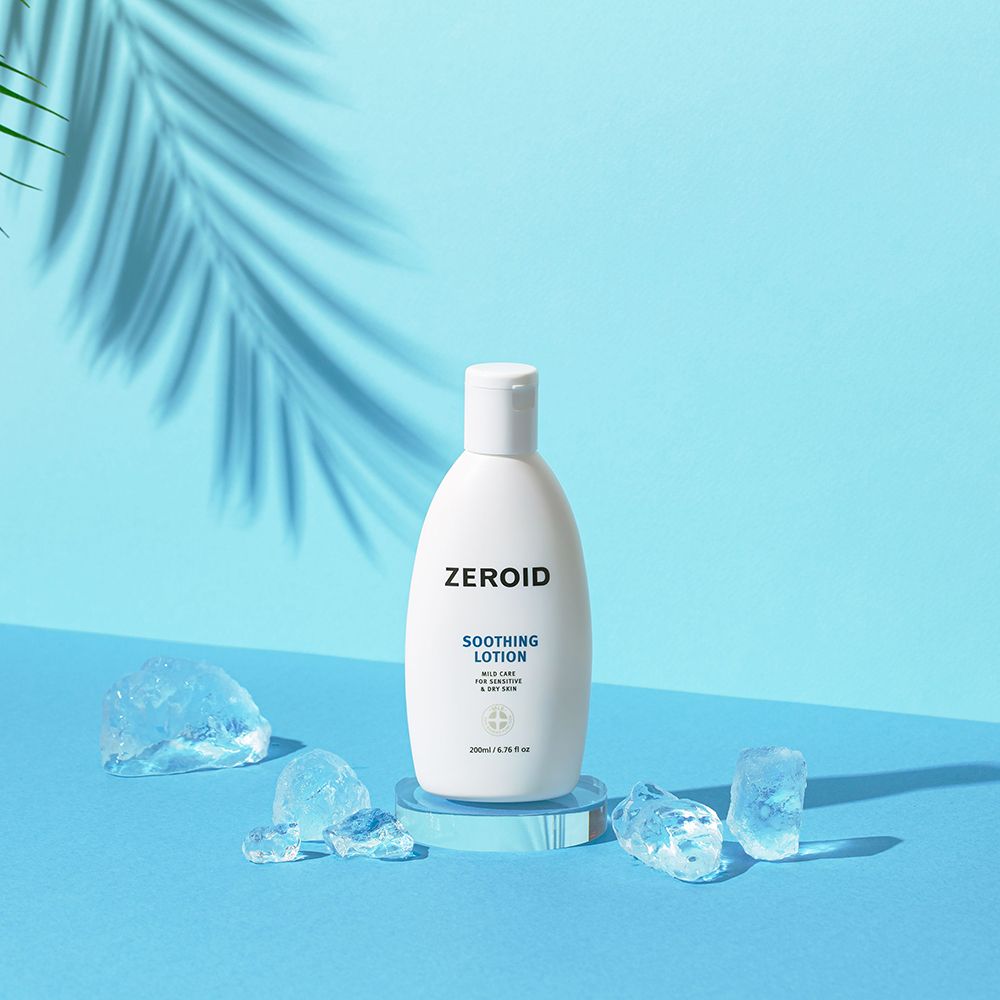 Flacone bianco ZEROID Soothing Lotion su piedistallo blu, circondato da cubetti di ghiaccio. 200ml/6.76 fl oz. Con ombra.