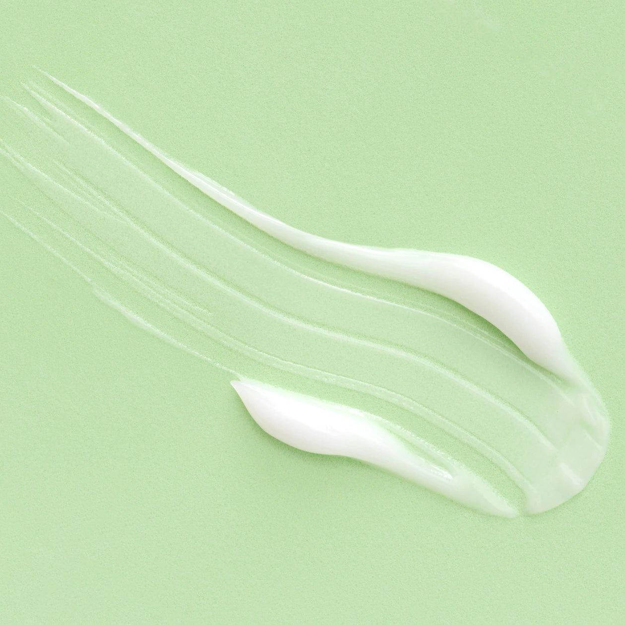 Prodotto in crema bianca su sfondo verde chiaro. Diverse strisce cremose si estendono sulla superficie.