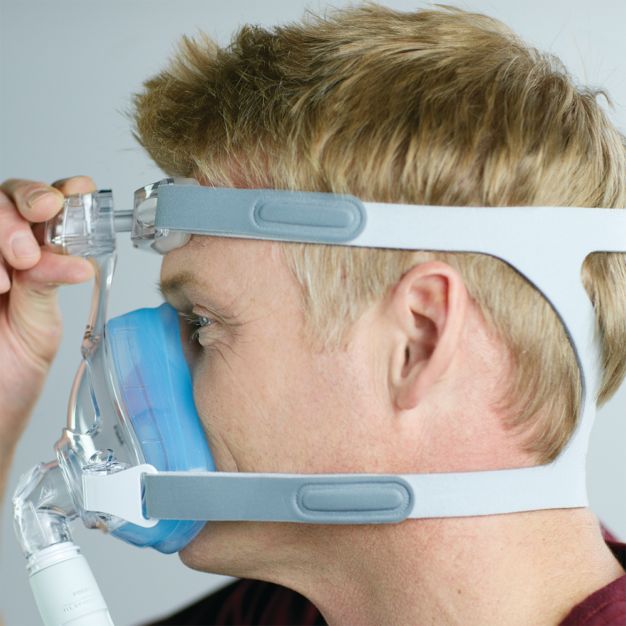 Vista laterale: uomo che regola la maschera CPAP Philips Amara SE Gel Full.