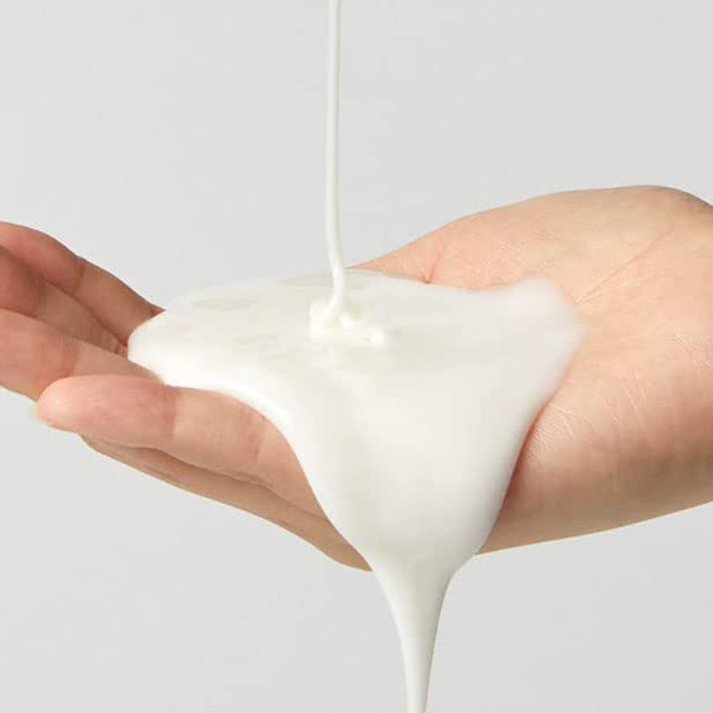 Crema maschera bianca che cola su una mano aperta.