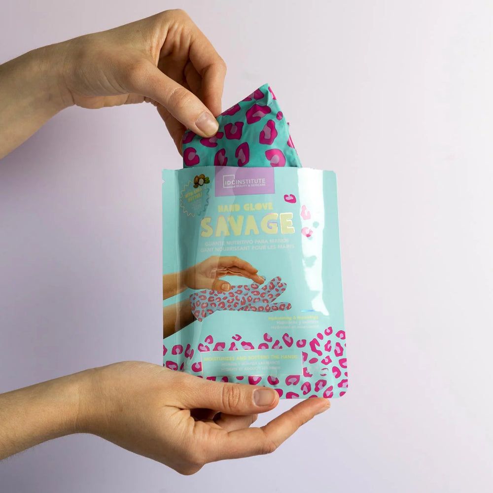 Mani che tengono una confezione aperta con una maschera per le mani. Maschera per le mani con stampa leopardata. Testo: IDC Institute, Savage.
