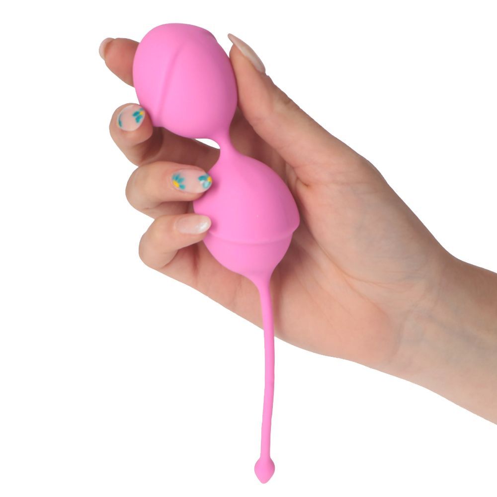 Palline vaginali rosa tenute in mano. Due sfere collegate da un gambo. In silicone.