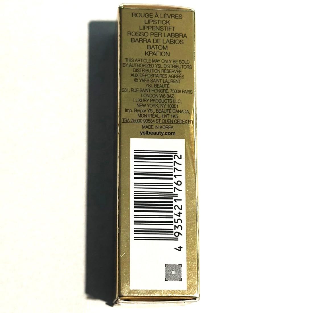 Lato della confezione dorata con informazioni sul prodotto e codice a barre. Testo multilingue.