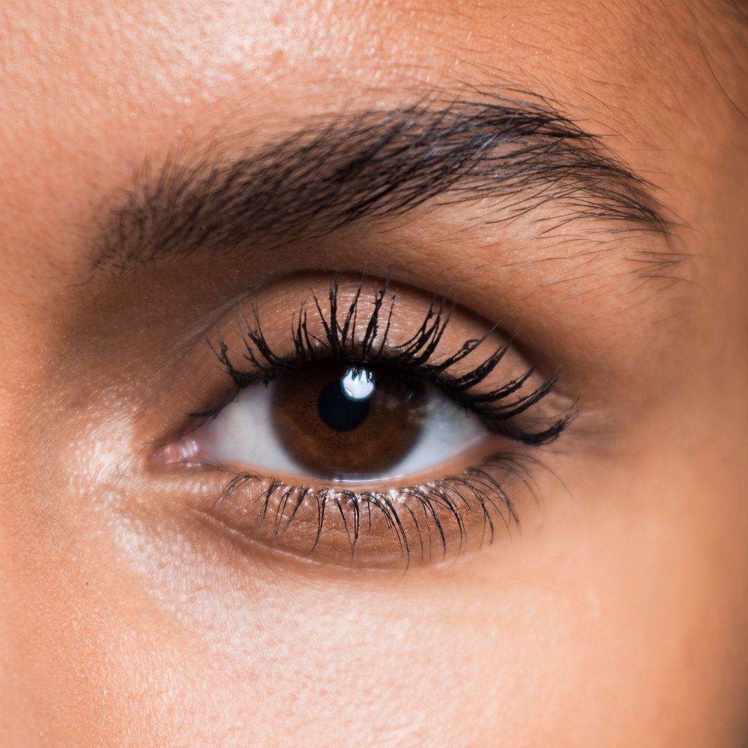 Primo piano di un occhio. Iride marrone, ciglia scure, sopracciglio scuro. Tono della pelle.