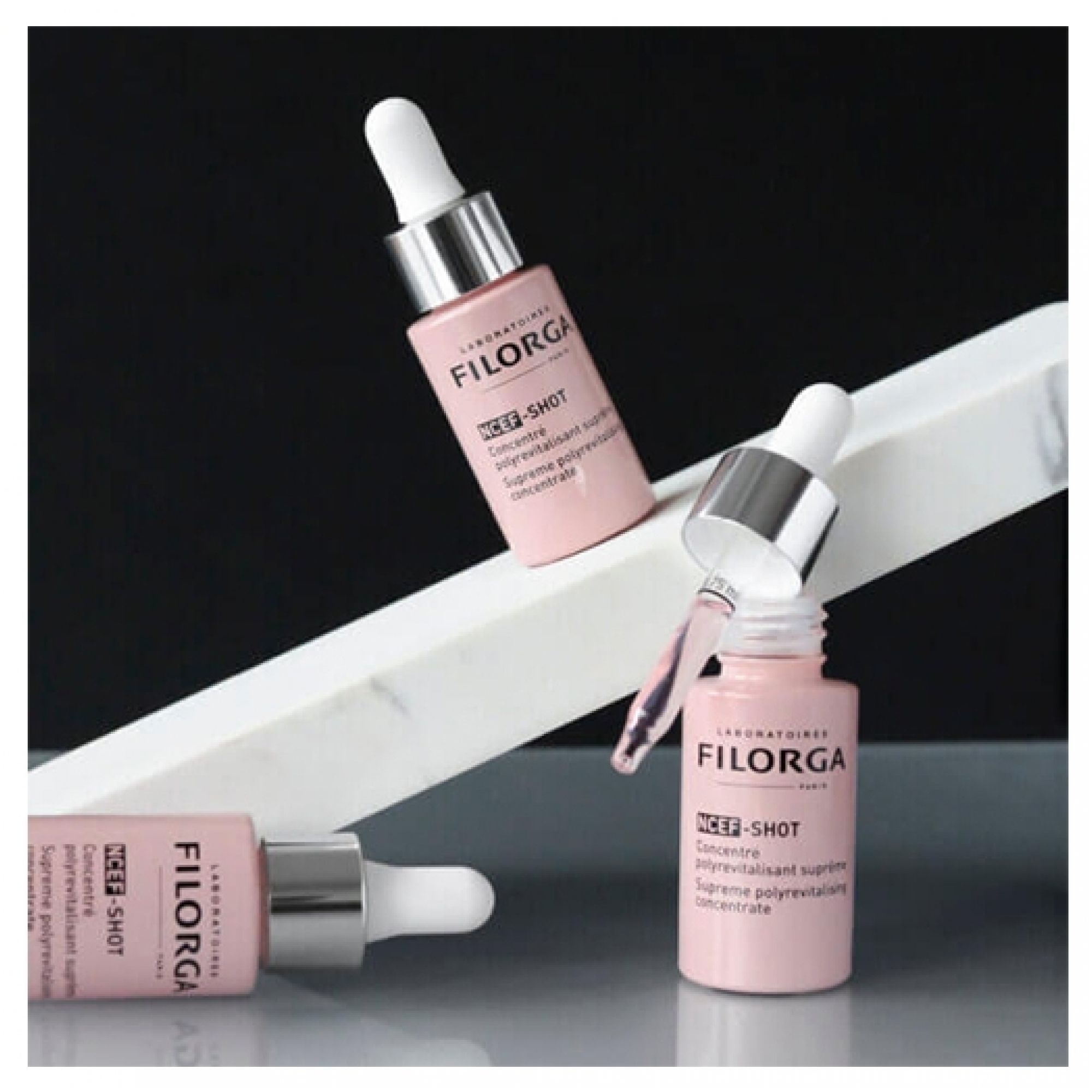 Tre flaconi contagocce rosa con tappi argentati e contagocce bianco, un flacone è aperto.
