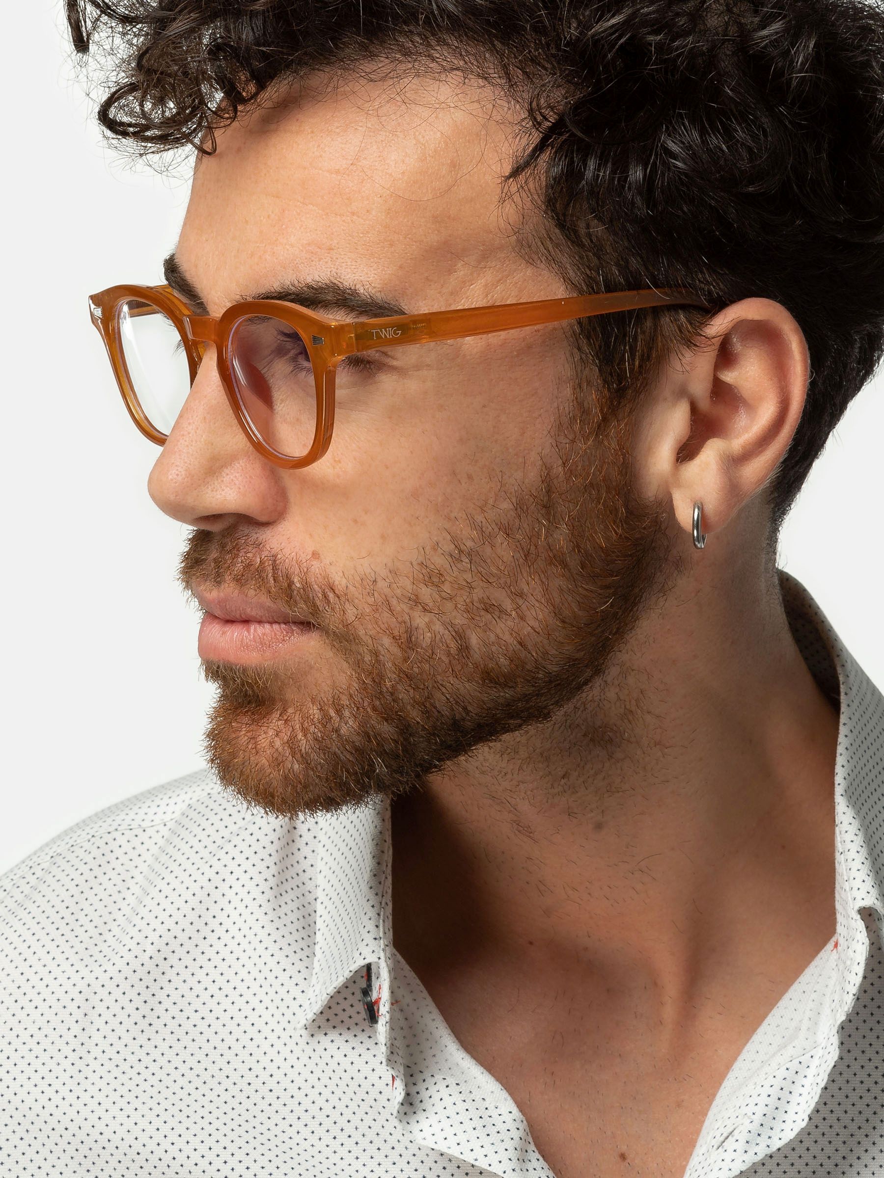 Uomo con occhiali, profilo. Occhiali rotondi, arancioni. L'uomo guarda di lato.