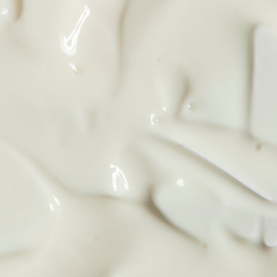 Primo piano di una crema bianca. La crema ha una consistenza liscia e lucida.