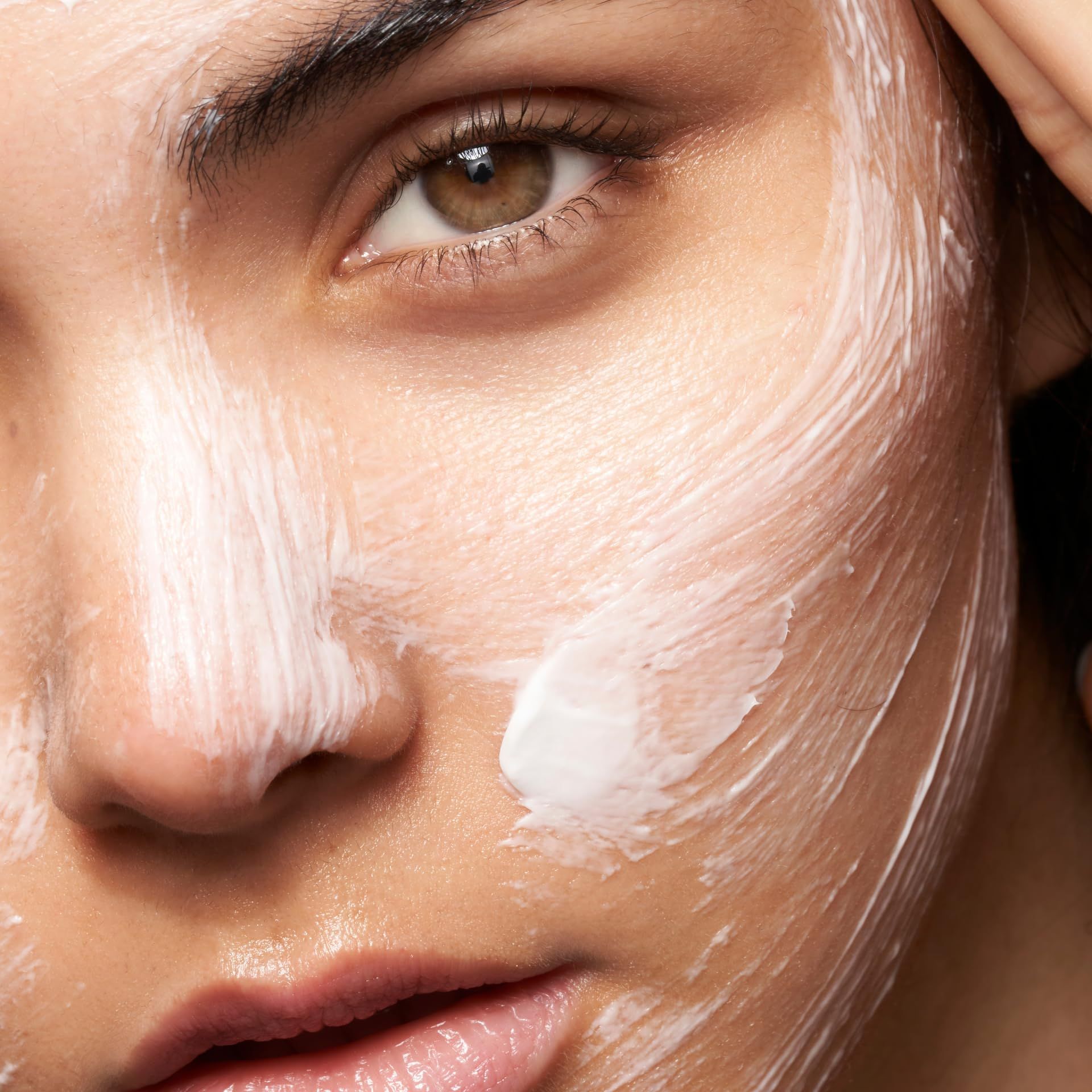 Primo piano di un viso con crema bianca. Crema visibile sulla pelle.