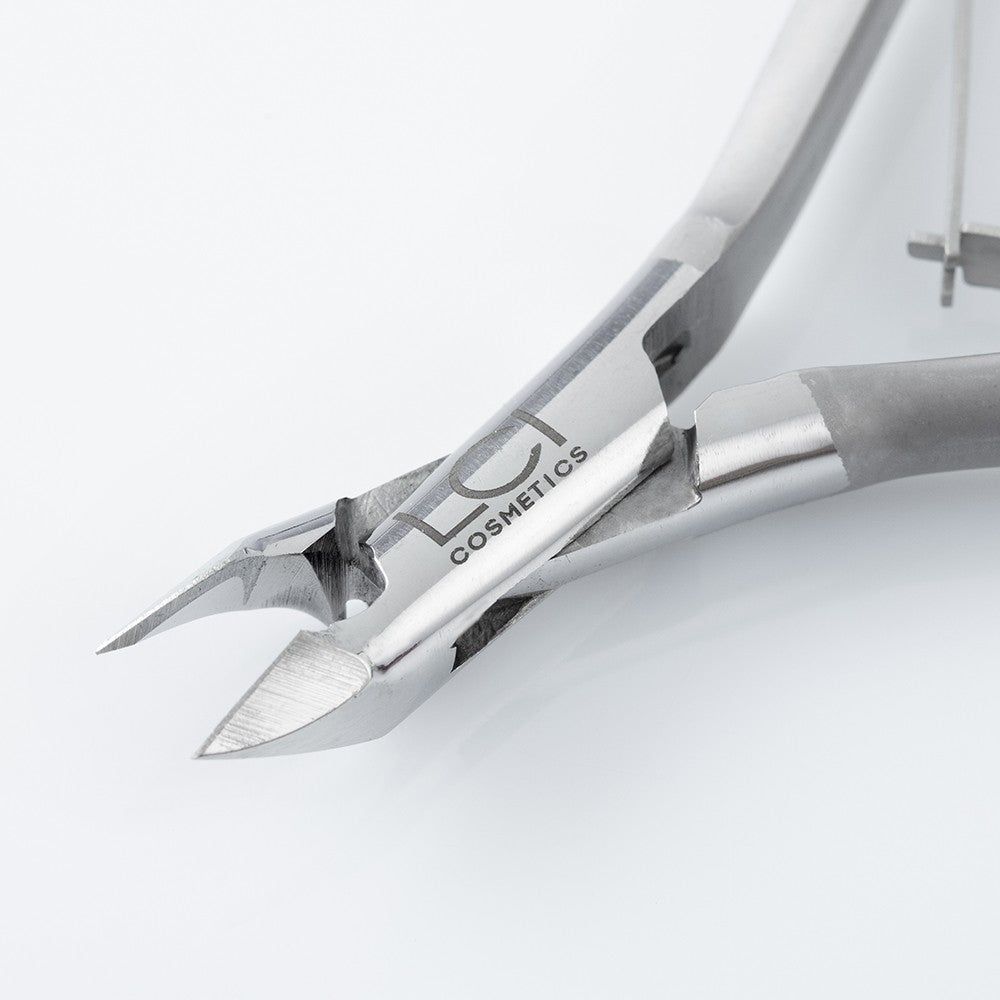 Primo piano della tronchesina. Taglio arrotondato, metallo. Logo LCI Cosmetics.