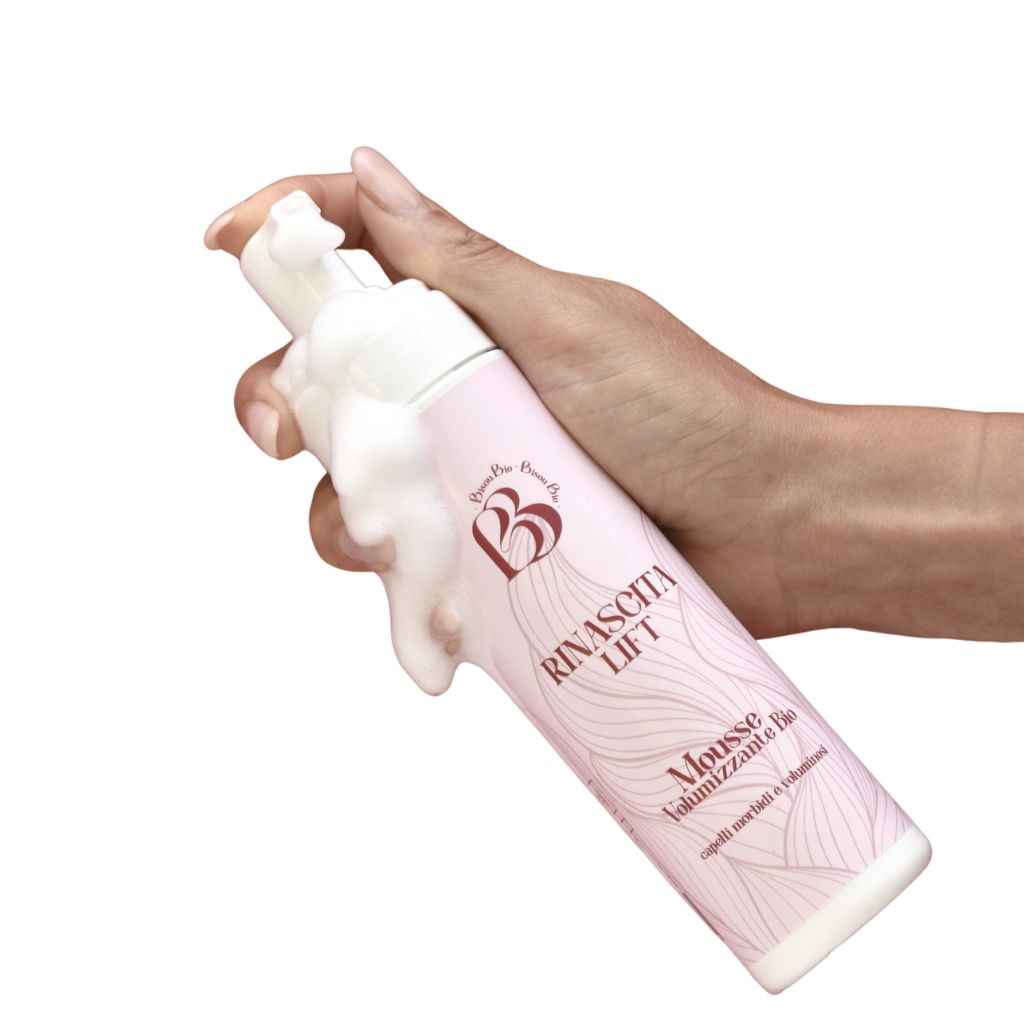 Mano tiene flacone rosa con erogatore. Fuoriesce schiuma. Scritta: Rinascita Lift, Mousse Volumizzante Bio.