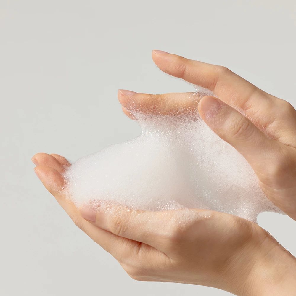 Mani con gel detergente schiumoso. Schiuma bianca e fine tra le dita.