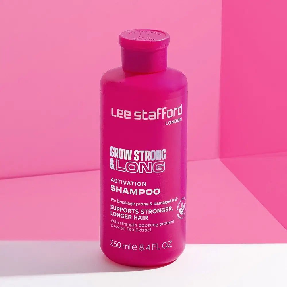 Flacone di shampoo attivatore LEE STAFFORD Grow Strong & Long su sfondo rosa.