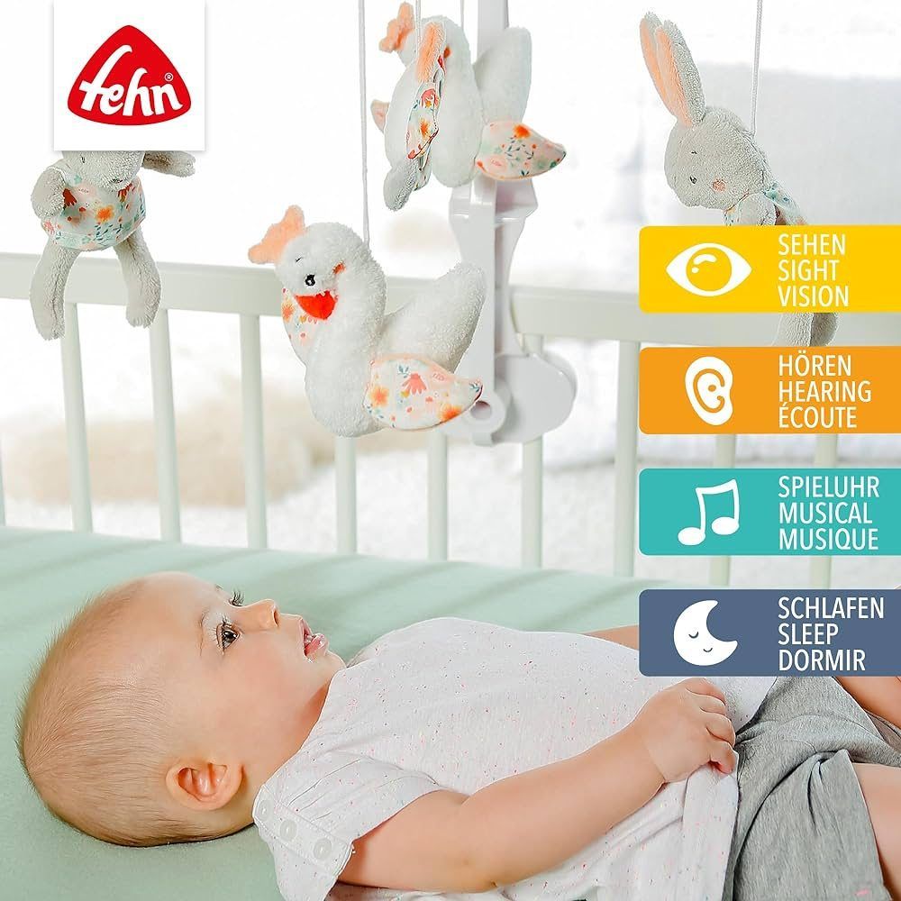Bambino sotto il mobile. Mobile con conigli, cigni e specchio. Logo Fehn. Pittogrammi per vedere, sentire, carillon, dormire.