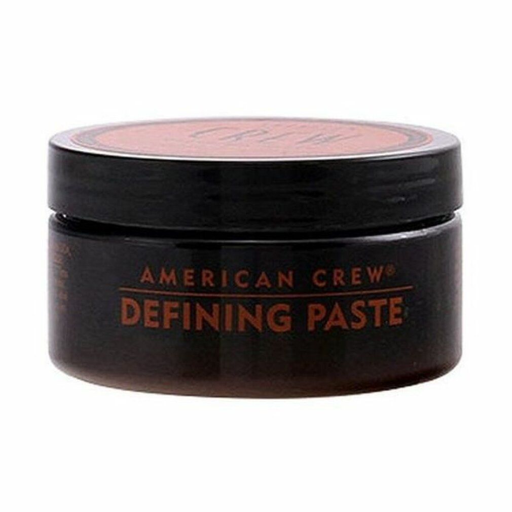 Barattolo cilindrico con corpo e coperchio marrone. "AMERICAN CREW DEFINING PASTE" in marrone. Coperchio nero.