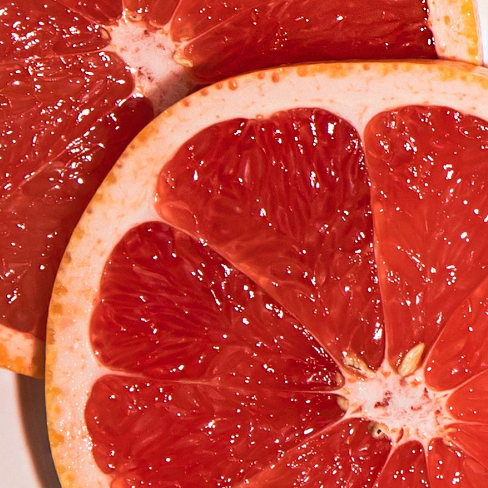 Due metà di pompelmo rosso e succoso. La buccia è rosa chiaro. Primo piano.