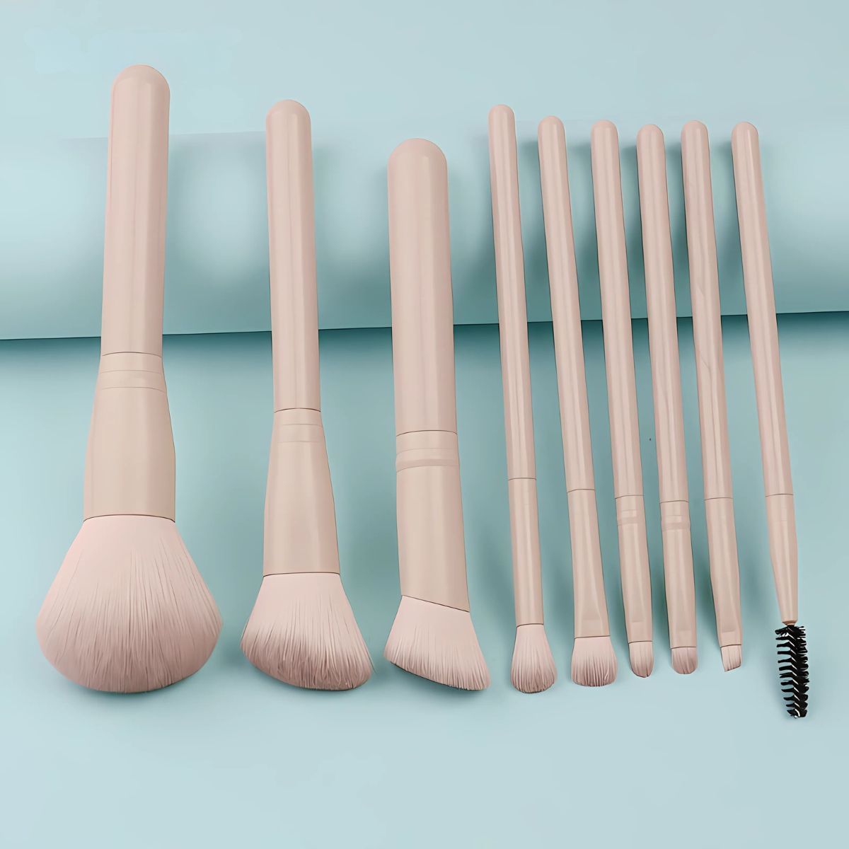 Un set di otto pennelli per il trucco beige chiaro con teste diverse e una spazzola a spirale.
