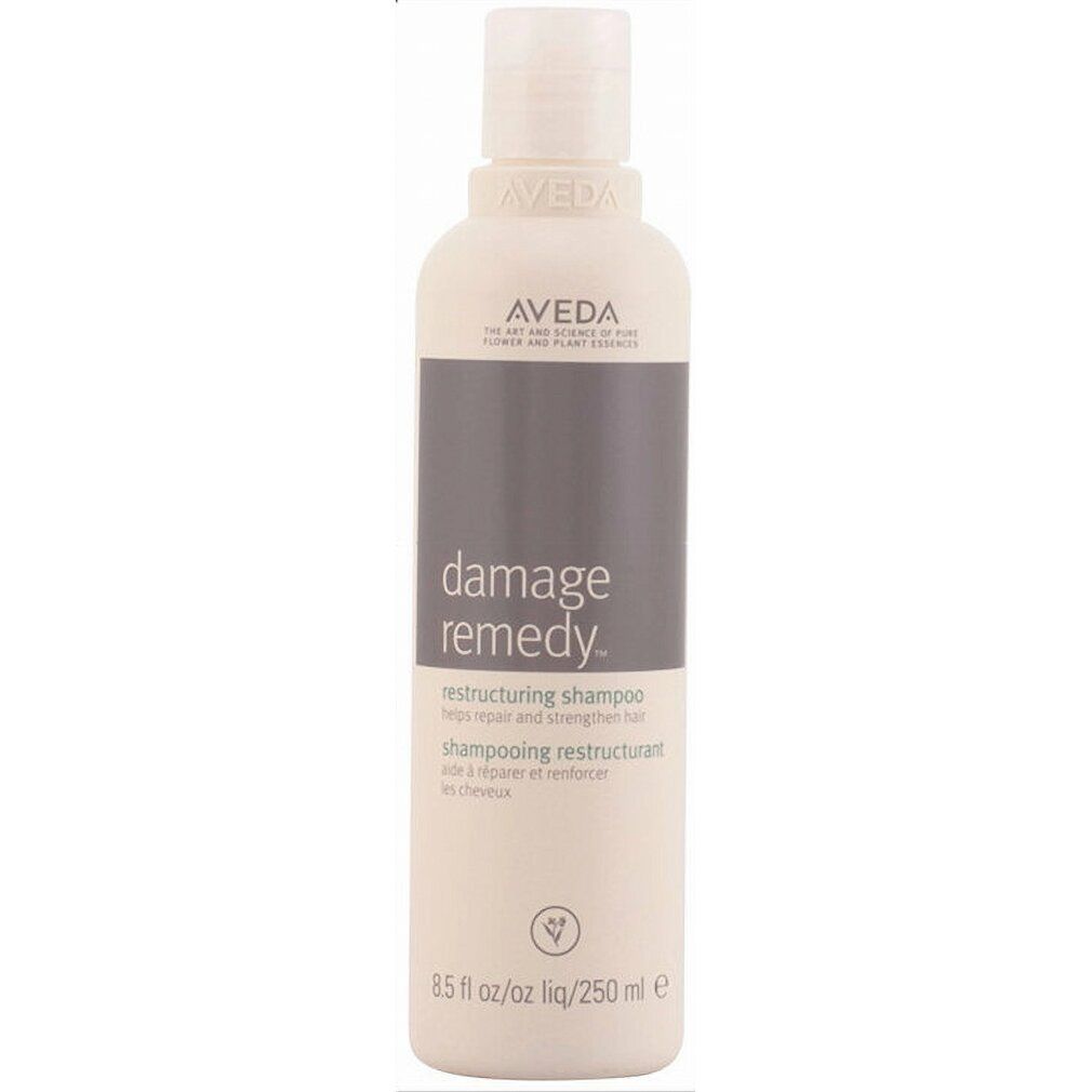 Flacone di shampoo beige con etichetta grigia. Scritta: Aveda, Damage Remedy, Restructuring Shampoo. 250 ml.