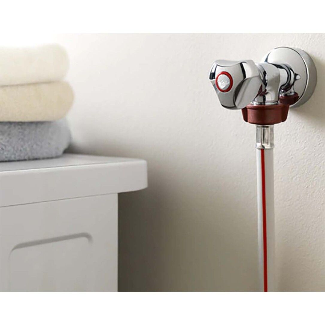 Rubinetto cromato con raccordo marrone e tubo bianco-rosso. Asciugamani sullo sfondo.