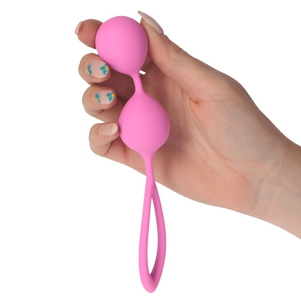 Sfera rosa collegata con anello. Tenuta in mano con unghie chiare.