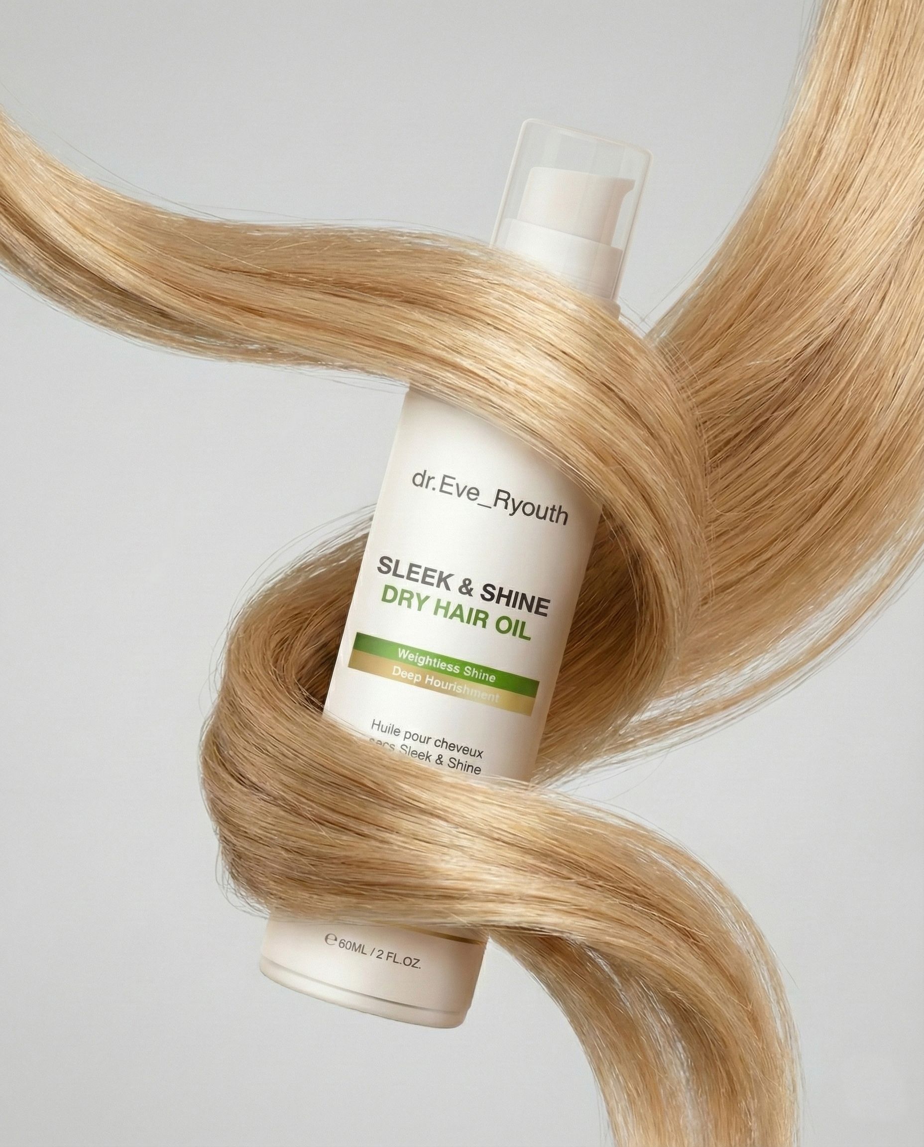 Una bottiglia di olio secco Sleek & Shine è circondata da lunghi capelli biondi.