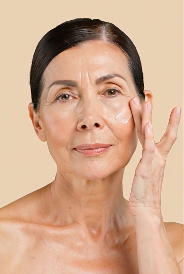 Donna anziana applica la crema sul viso. Crema sul dito.