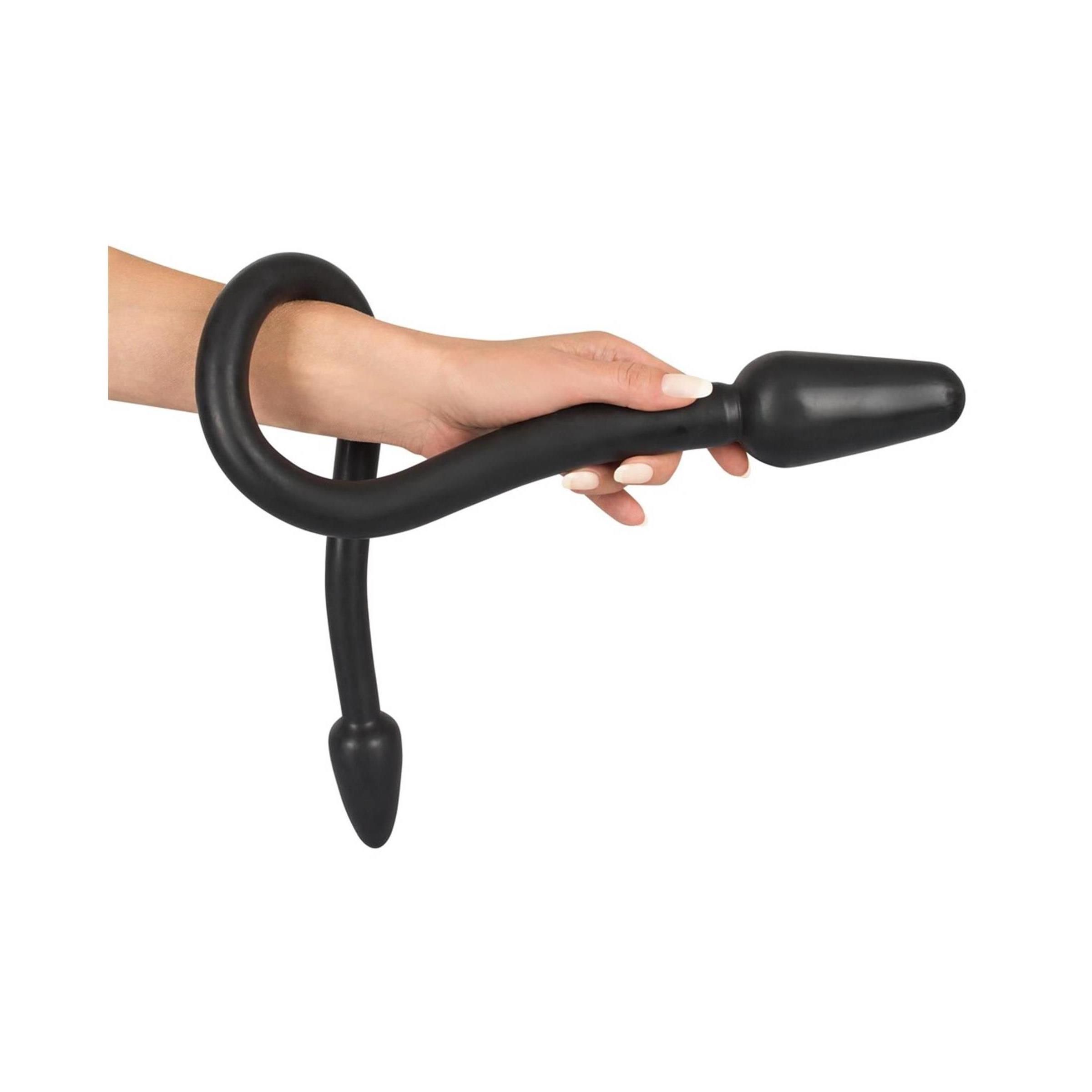 Mano che tiene un dildo nero con estremità coniche.