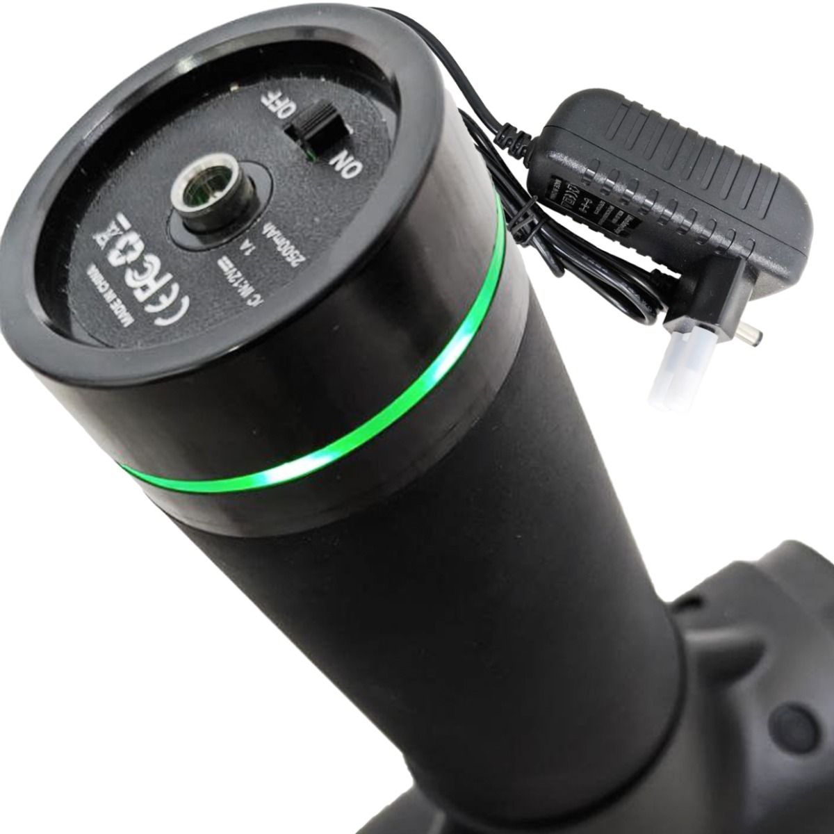 Primo piano dell'estremità della pistola massaggiante con porta di ricarica e interruttore on/off. Illuminazione a LED verde.