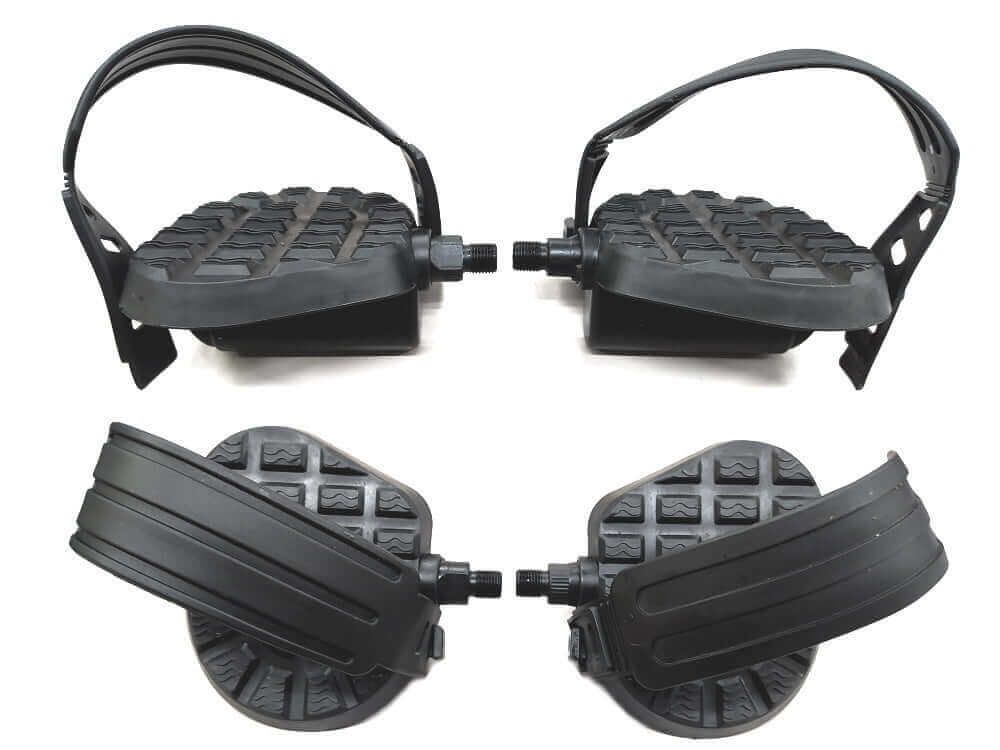 Quattro pedali neri per bicicletta con cinghie. I pedali hanno una superficie strutturata e un supporto curvo.