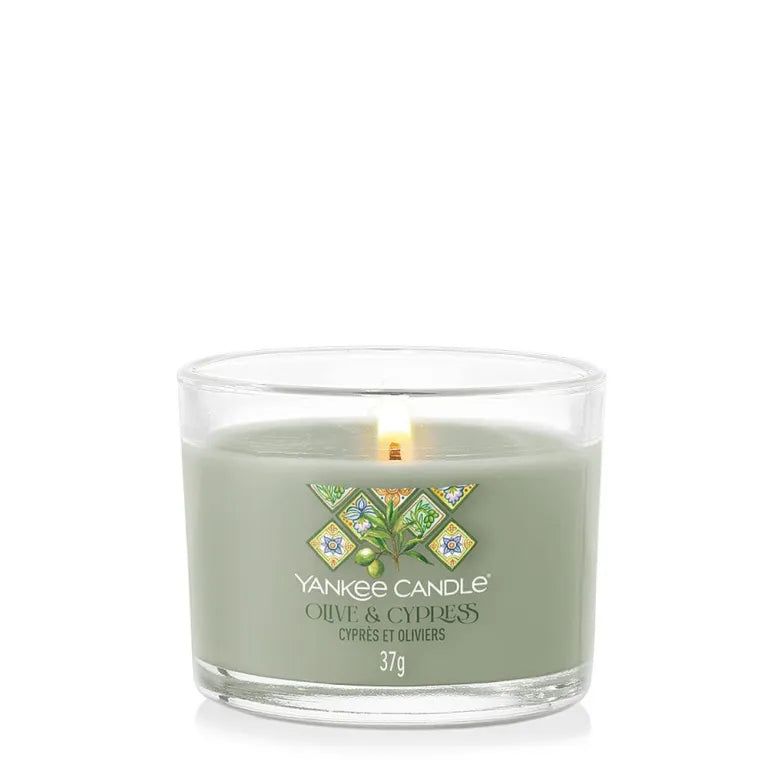 Candela verde in contenitore di vetro. Etichetta Olive & Cyprès. Scritta: Yankee Candle, Olive & Cypress, 37g. Stoppino acceso.