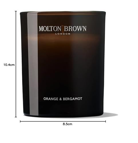 Candela profumata in vetro scuro con logo bianco e scritta "Orange & Bergamot". Dimensioni: 10,4 cm altezza, 8,5 cm larghezza.