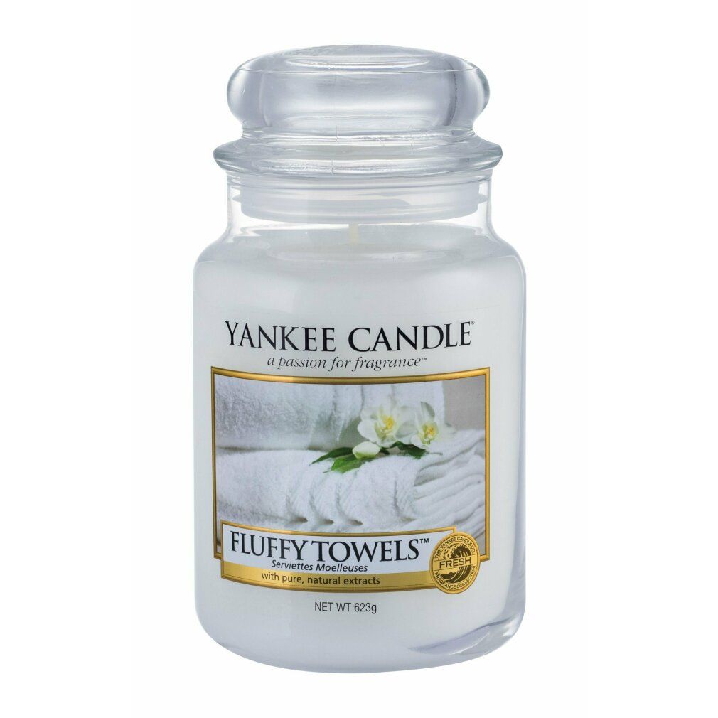 Candela profumata Fluffy Towels di Yankee Candle. Contenitore in vetro con coperchio. Etichetta con asciugamani e fiori. Netto 623g.