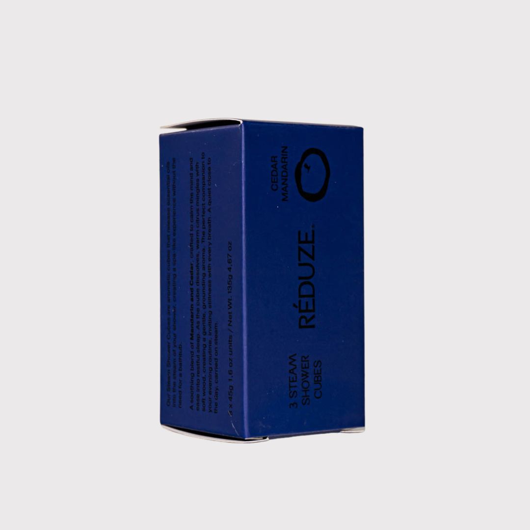 Scatola blu con informazioni sul prodotto. RÉDUZE. Profumo Cedro Mandarino. 3 Steam Shower Cubes. Vista laterale.