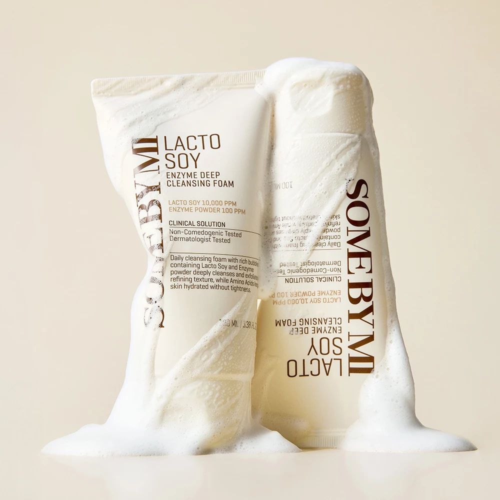 Due tubetti di schiuma detergente bianca, ricoperti di schiuma. Sui tubetti c'è scritto "Lacto Soy Enzyme Deep Cleansing Foam".