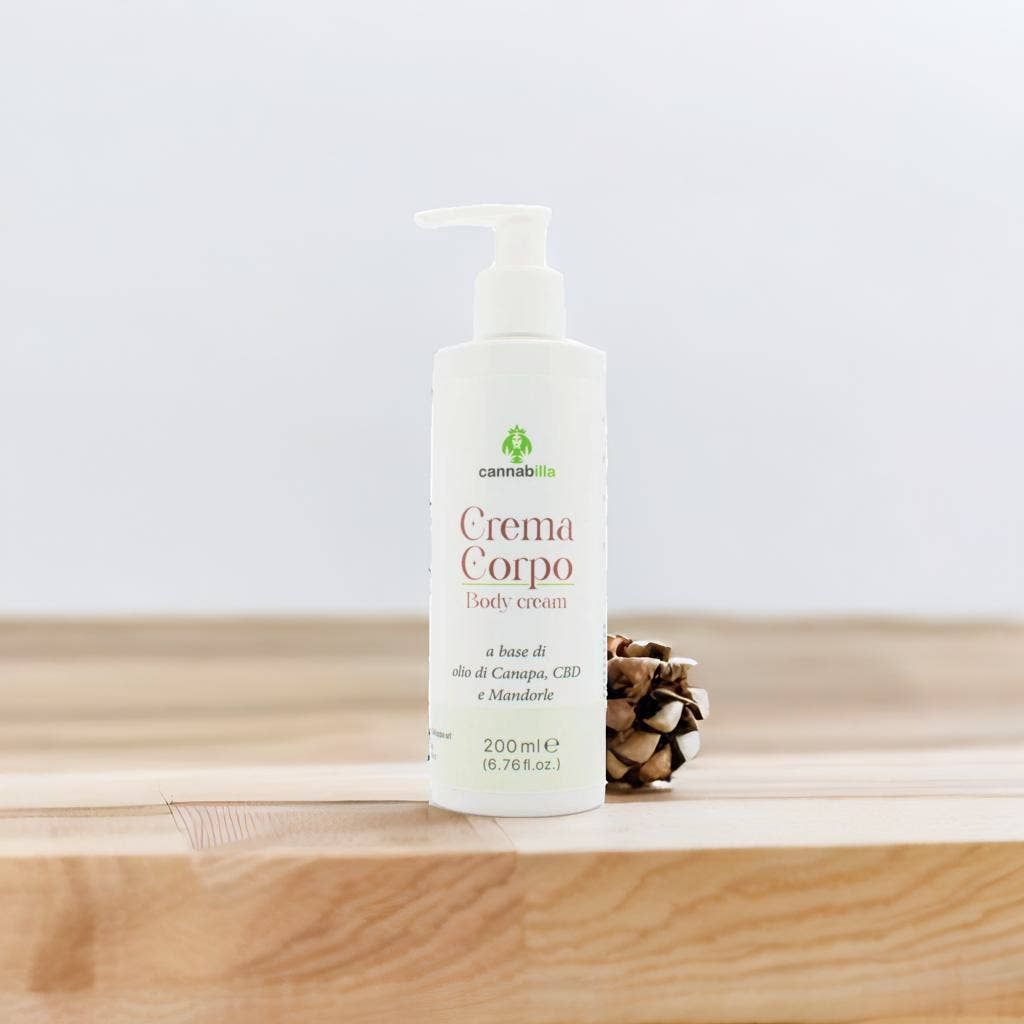 Flacone bianco con dosatore. Scritta: Crema Corpo, Body cream. Contiene olio, CBD e mandorle. 200 ml. Su superficie in legno.