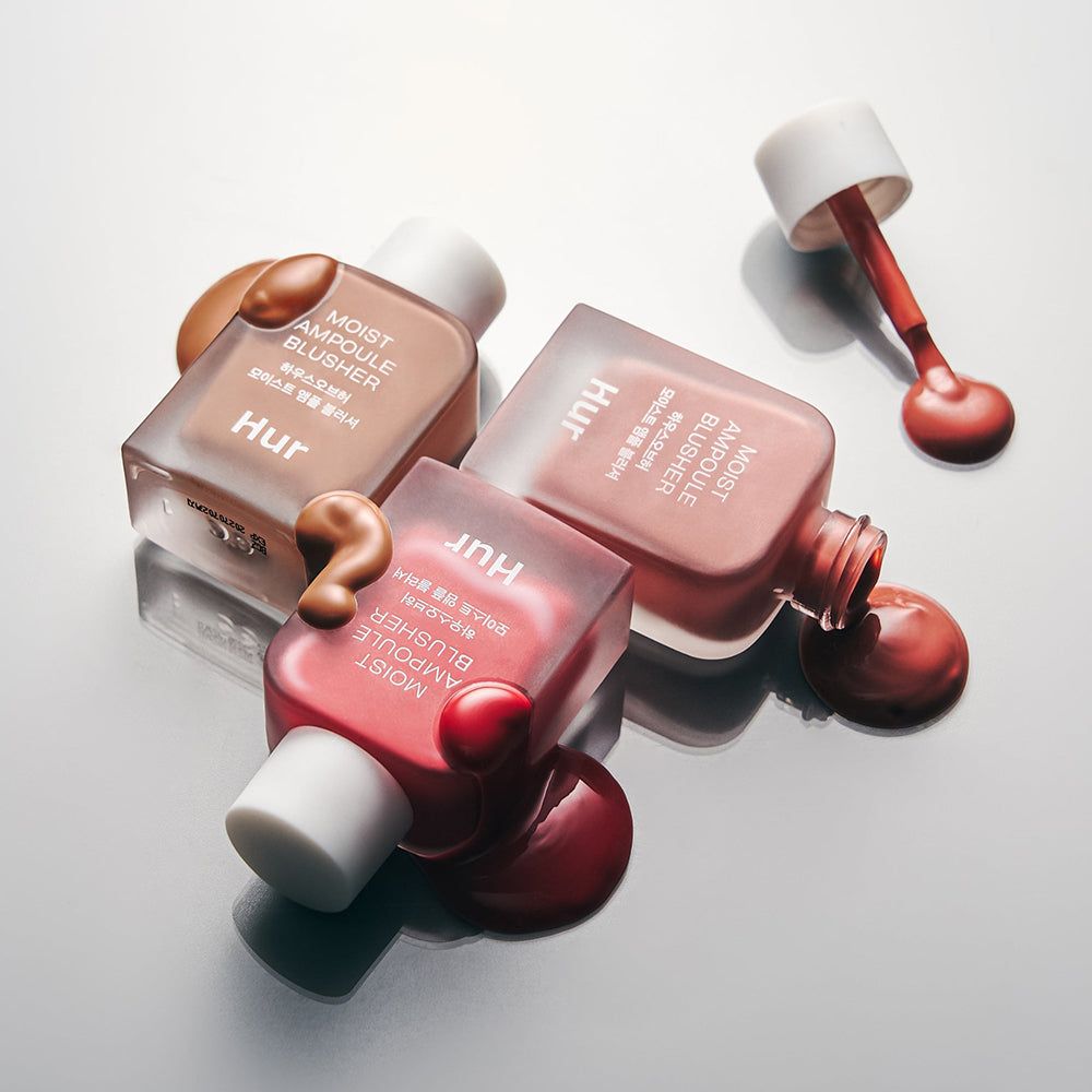Tre bottiglie 'Moist Ampoule Blusher' sono appoggiate. Prodotto su sfondo. Colori: Nude Beige, Rosa e una tonalità più scura.