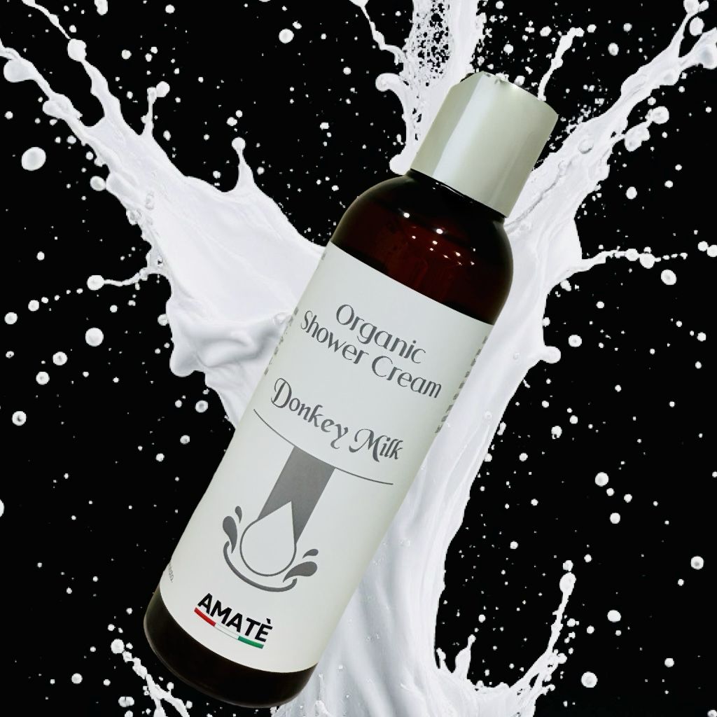 Flacone davanti a spruzzi di latte. Scritta: Organic Shower Cream Donkey Milk. Marchio: Amatè.