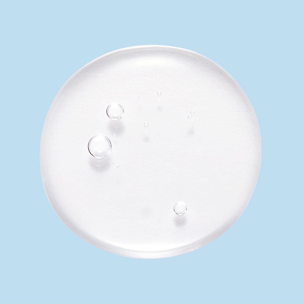 Dischetto tonico rotondo e trasparente con bolle su sfondo azzurro.