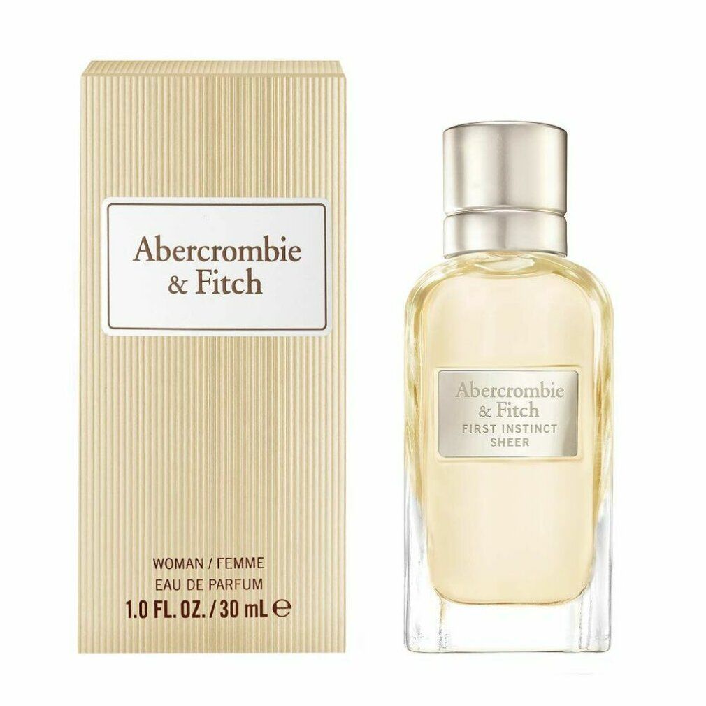Flacone di profumo e scatola. L'etichetta riporta "Abercrombie & Fitch First Instinct Sheer". La scatola indica "WOMAN / FEMME".