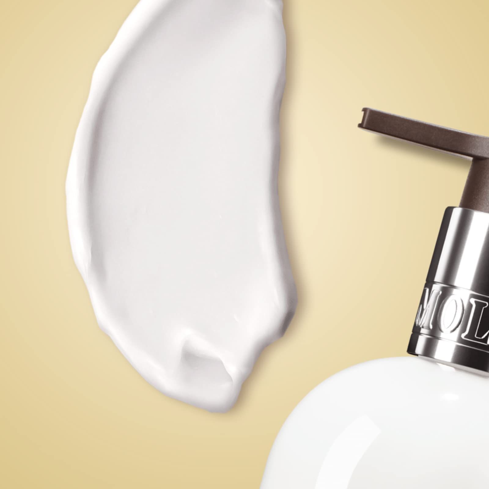 Macchia bianca di lozione per il corpo accanto a un flacone. Scritta: Molton Brown.