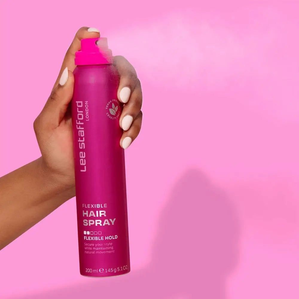 Mano che spruzza Lee Stafford Flexible Hairspray da un flacone rosa.