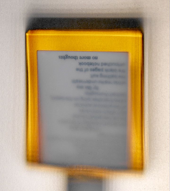 Rettangolo giallo con testo sfocato. Testo: no more thoughts, etc. Scritta: notebook.