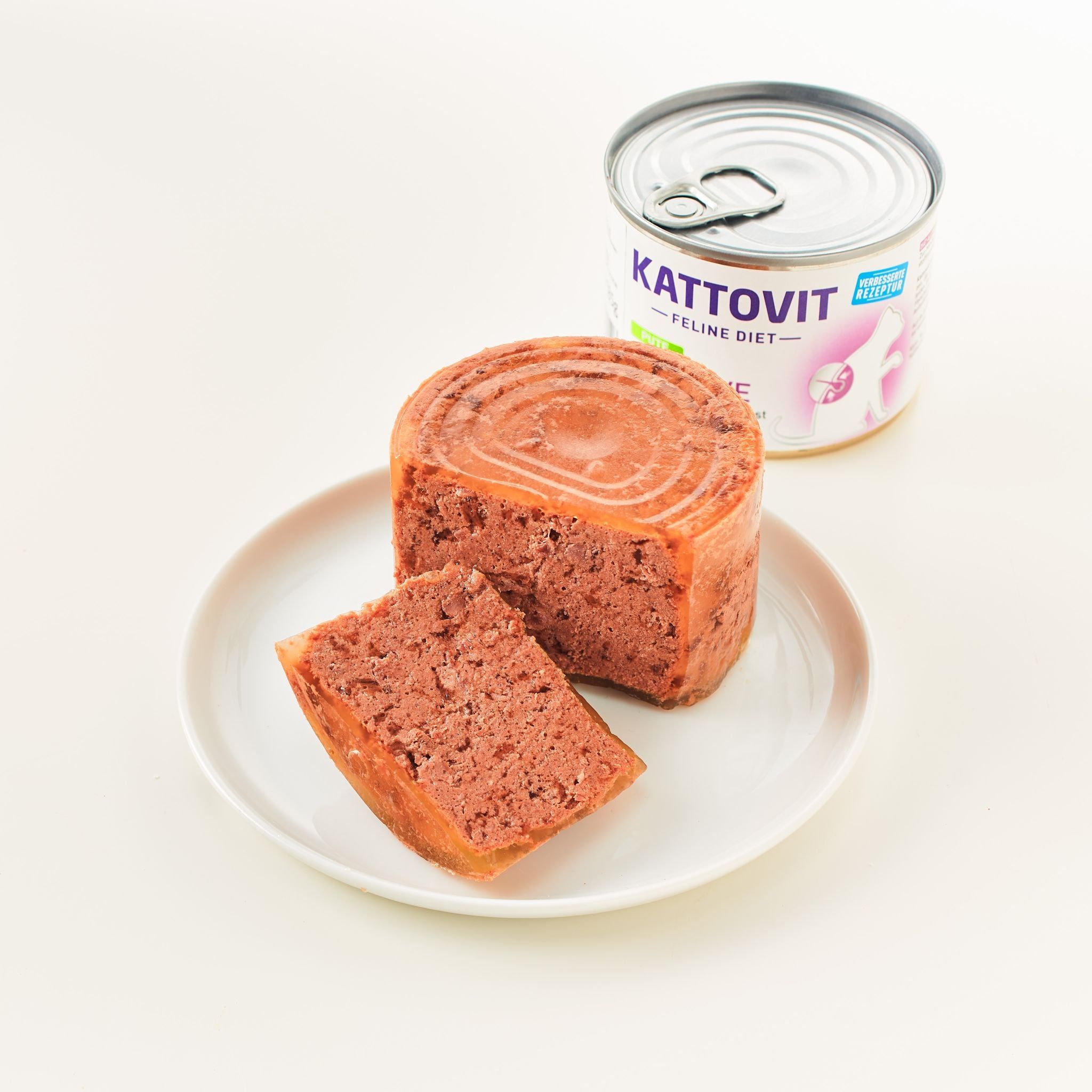 Lattina Kattovit Sensitive Huhn e pezzo di cibo su piatto. Pezzo di cibo con superficie tagliata. Etichetta: Huhn, Sensitive, Feline Diet.