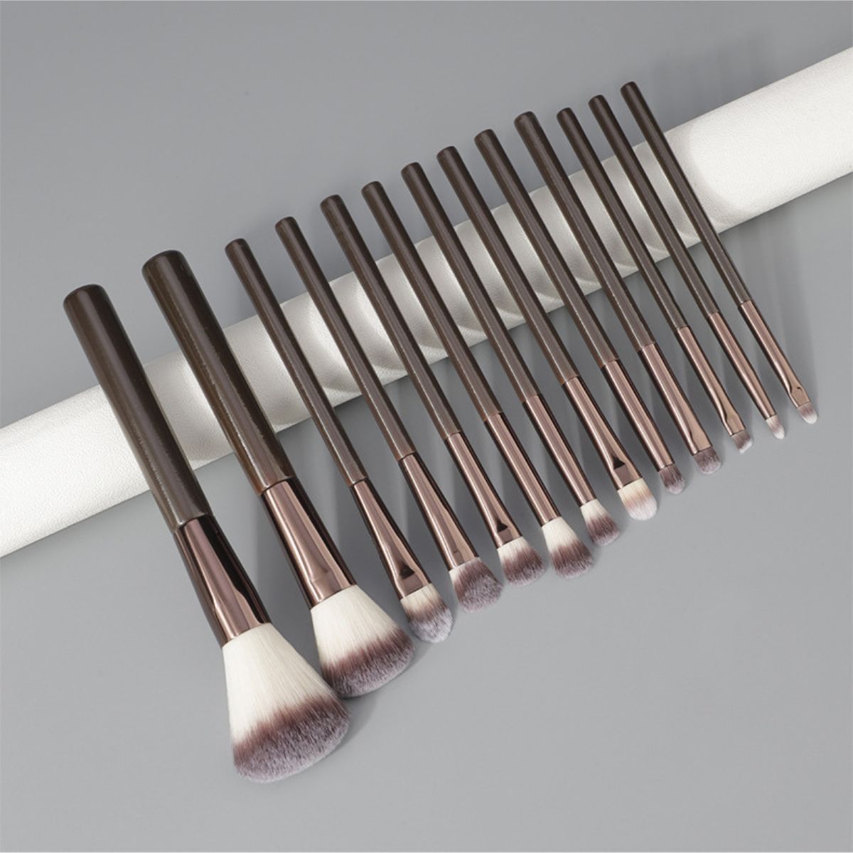 Un set di 12 pennelli per il trucco scuri con ghiere argentate e setole soffici.