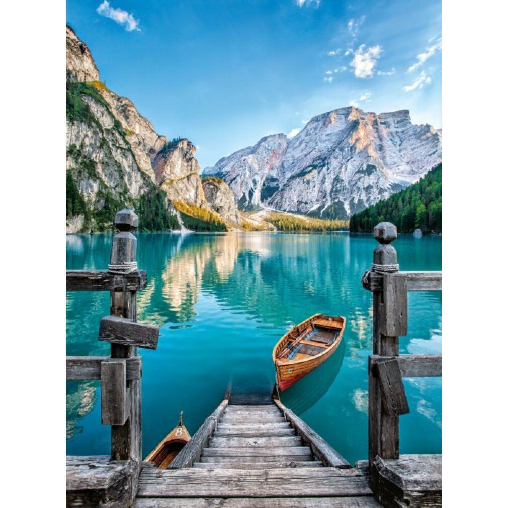 Puzzle paesaggistico con lago, barche e montagne. Passerella in legno che conduce all'acqua. Cielo blu con nuvole. 500 pezzi.