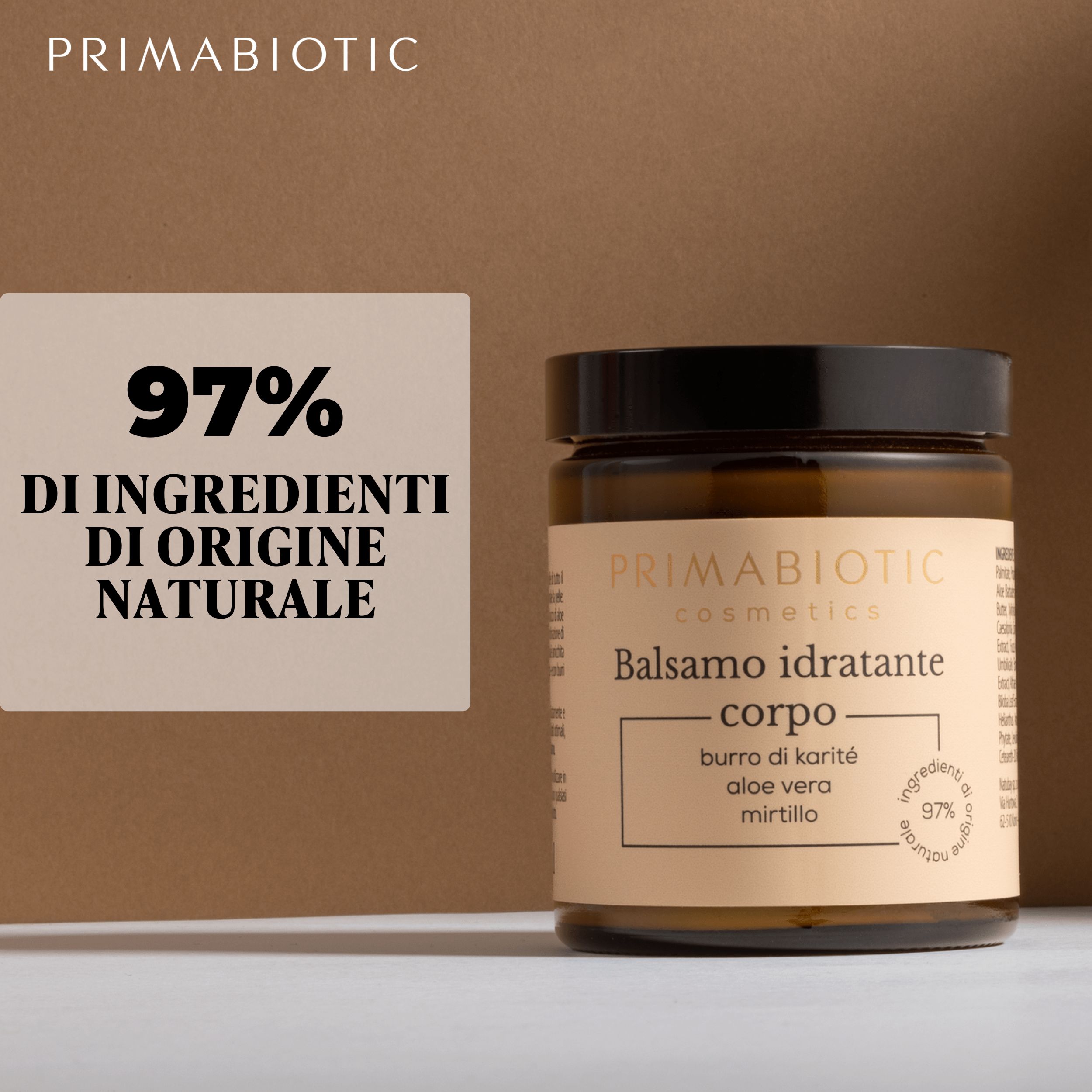 Vaso in vetro marrone con coperchio nero. L'etichetta recita: Balsamo idratante corpo, Primabiotic Cosmetics. 97% ingredienti di origine naturale.