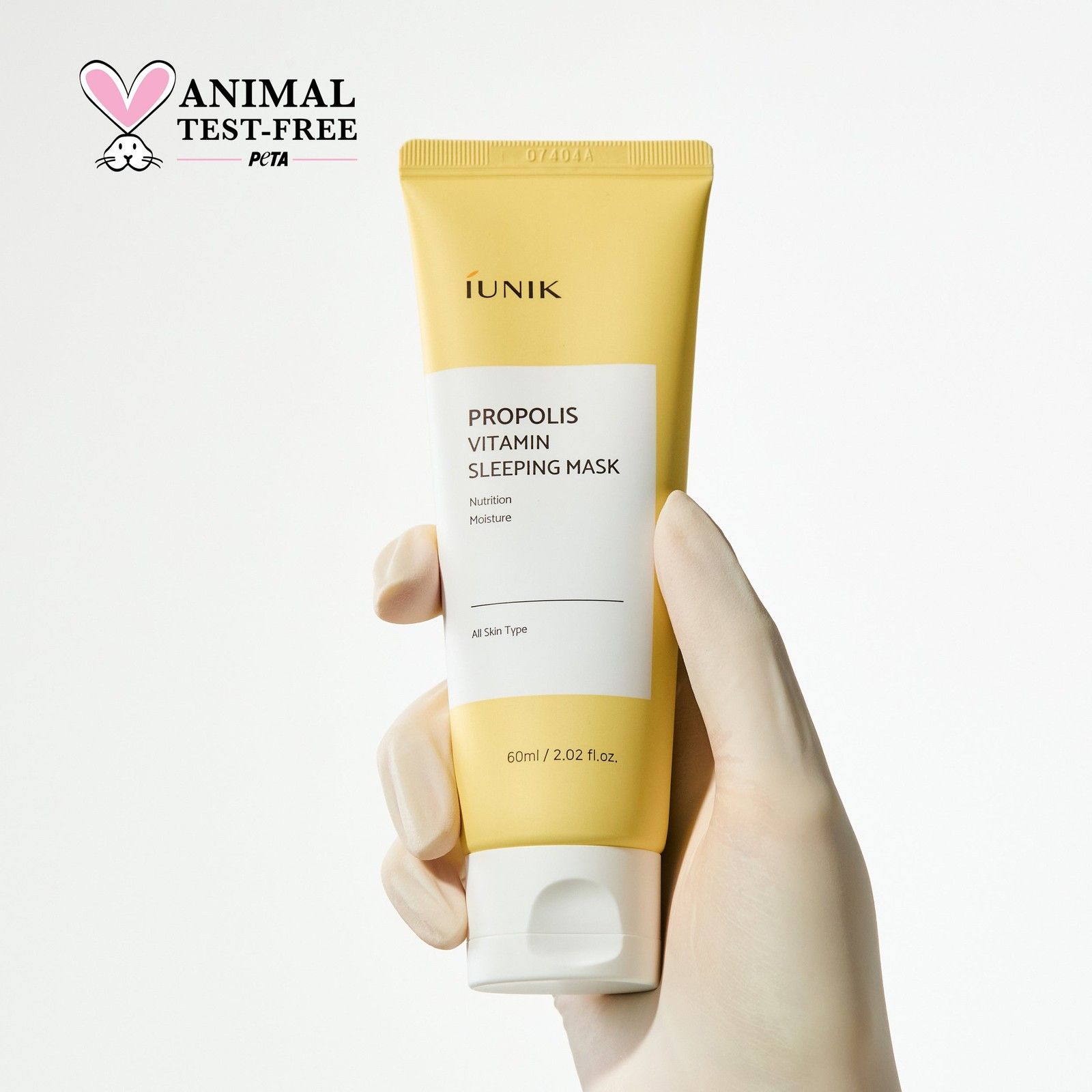 Mano che tiene il tubo di maschera da notte Propolis Vitamina iUNIK con sigillo PETA.