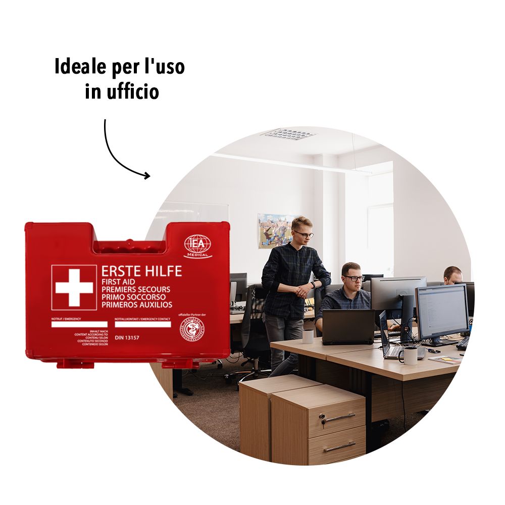 Cassetta di pronto soccorso rossa in ufficio. Persone sullo sfondo.