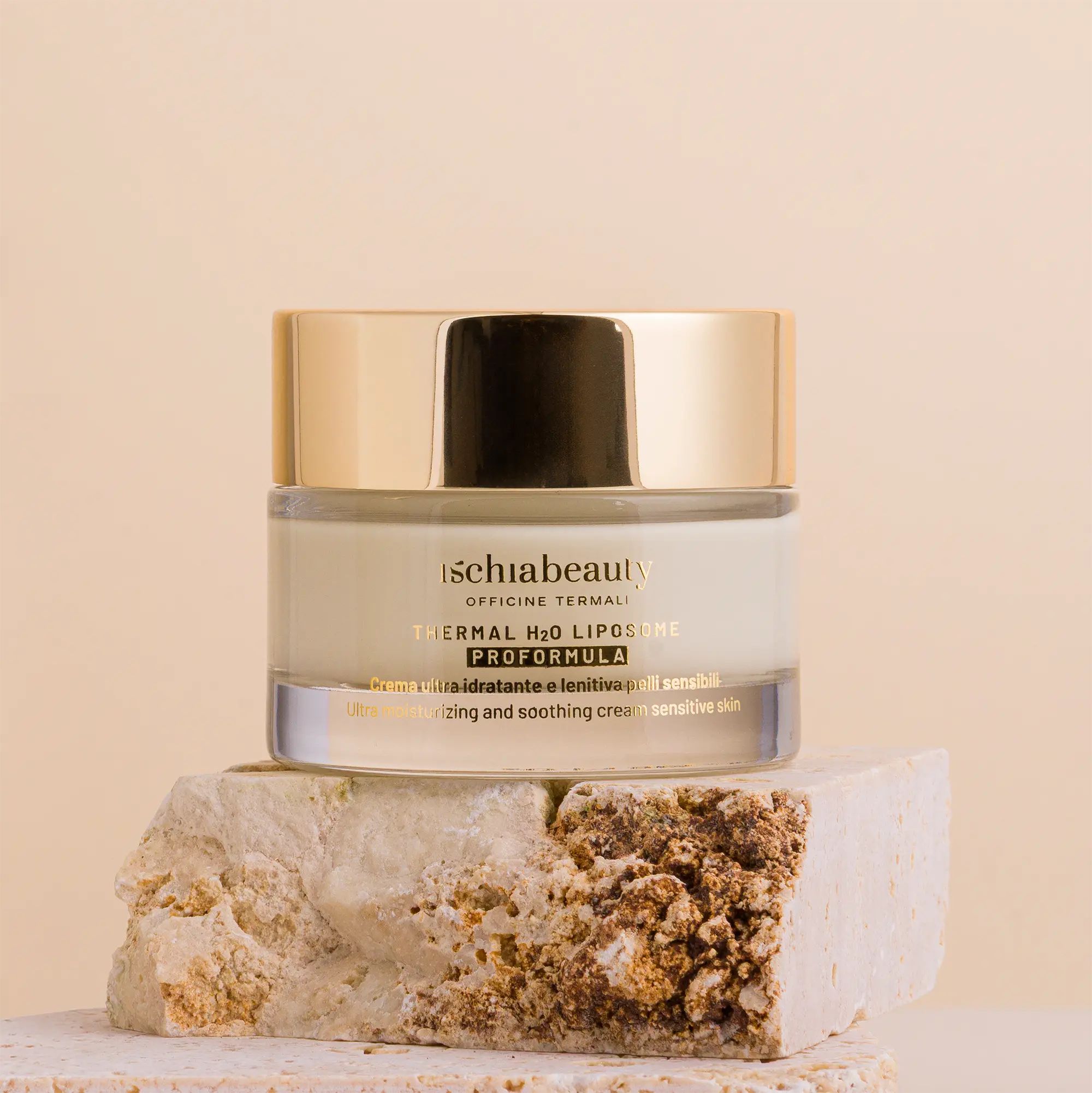 Vaso di crema con coperchio dorato. Testo: ischiabeauty, Thermal H2O Liposome, Proformula. Su pietra.